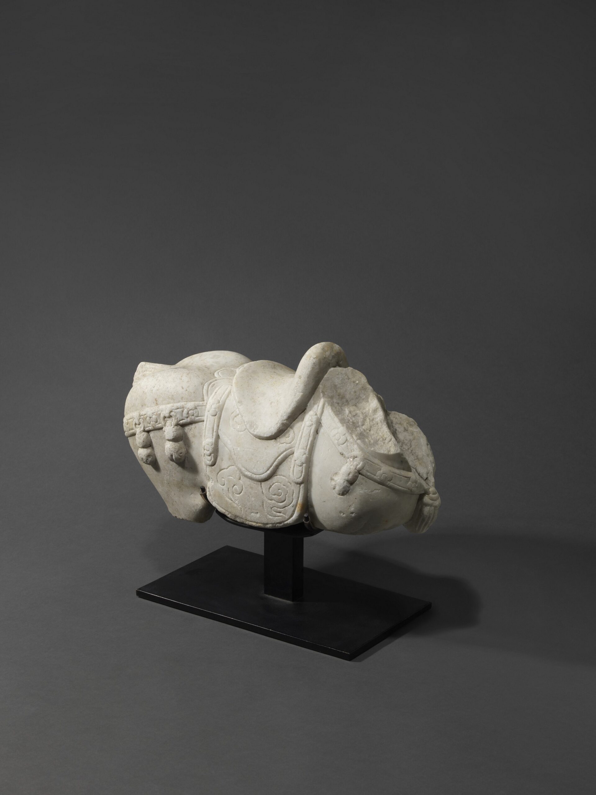 A white marble torso of a saddled horse