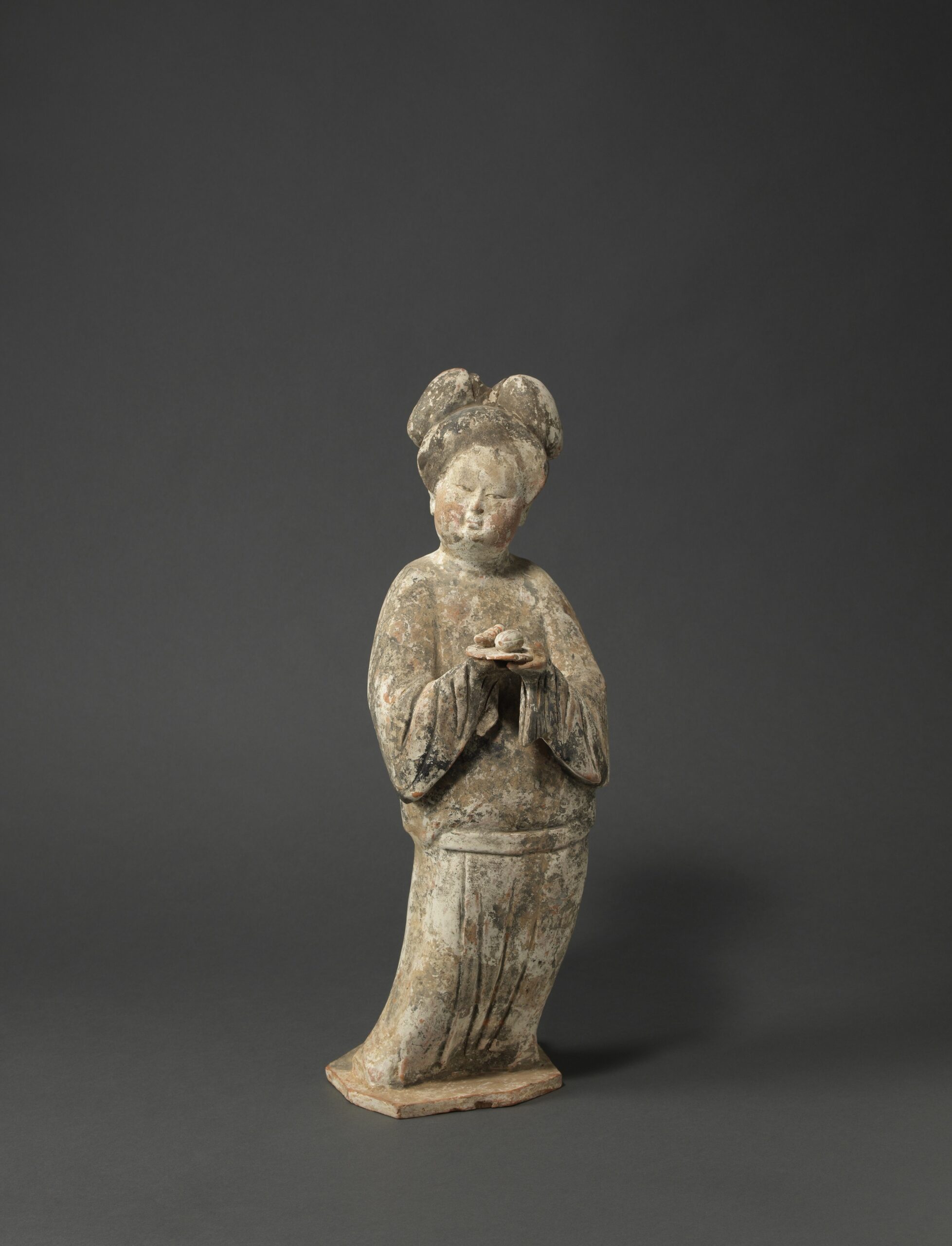 A PAINTED POTTERY FIGURE OF A COURT LADY HOLDING A DISH OF FRUIT Tang dynasty (618-906), first half 8th century Height: 46 cm, 18 inches 唐 彩繪陶捧盤仕女俑 高46釐米 A PAINTED POTTERY FIGURE OF A COURT LADY HOLDING A DISH OF FRUIT Tang dynasty (618-906), first half 8th century Height: 46 cm, 18 inches 唐 彩繪陶捧盤仕女俑 高46釐米