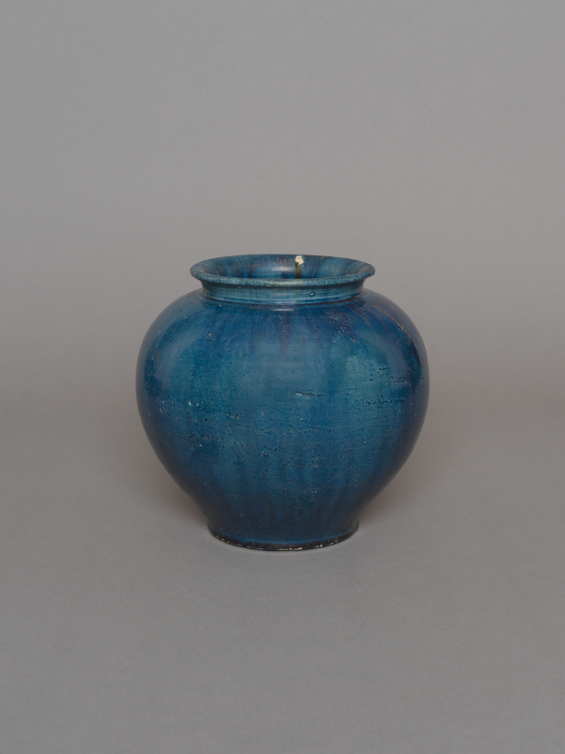 No. 6 - Chinese pottery blue glazed jar, guan, of well-rounded globular form with flat base and short flared neck, covered overall in a rich and even blue glaze extending in large splashes on the interior which also has a clear glaze, the rim with three spur marks from the firing. 8 1/8 inches, 21.7 cm high. Tang dynasty, Gongxian kilns, Henan Province, 7th – 8th century.
