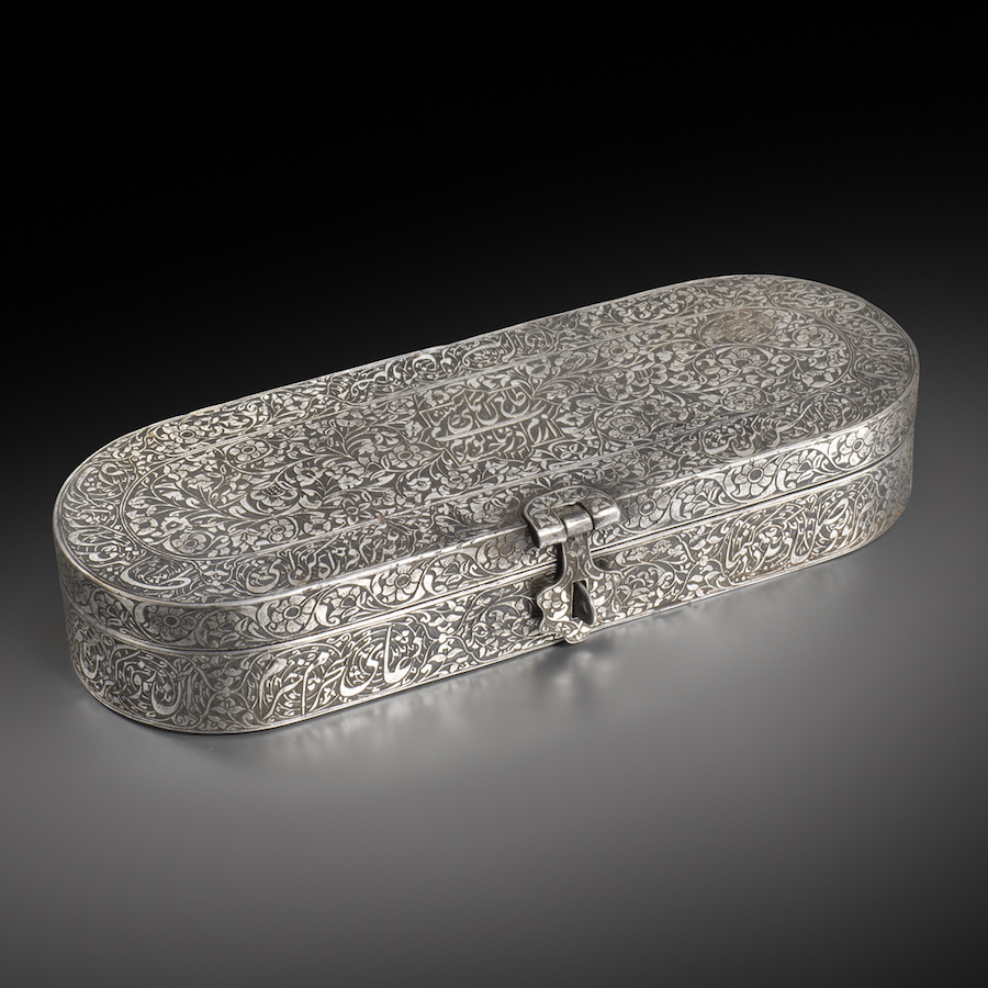 A Qajar steel pen-box inscribed to Gawhar Khanum, daughter of Fath ‘Ali Shah (r. 1797-1834)
Persia, dated A.H. 1231 / 1815-16 A.D.
Of cartouche form with twin hinges at the back and a floral clasp at the front, engraved with a dense design of flowering plants, enclosing on the top a cusped panel with the name and date, cusp-ended cartouches of nastal’iq around the borders and encircling the sides, the interior with an inner band of further inscriptions interrupted by four small ink-wells with hinged lids around a central vacant cartouche-shaped recess.
25.2 by 9 by 4.2 cm. A Qajar steel pen-box inscribed to Gawhar Khanum, daughter of Fath ‘Ali Shah (r. 1797-1834)
Persia, dated A.H. 1231 / 1815-16 A.D.
Of cartouche form with twin hinges at the back and a floral clasp at the front, engraved with a dense design of flowering plants, enclosing on the top a cusped panel with the name and date, cusp-ended cartouches of nastal’iq around the borders and encircling the sides, the interior with an inner band of further inscriptions interrupted by four small ink-wells with hinged lids around a central vacant cartouche-shaped recess.
25.2 by 9 by 4.2 cm.