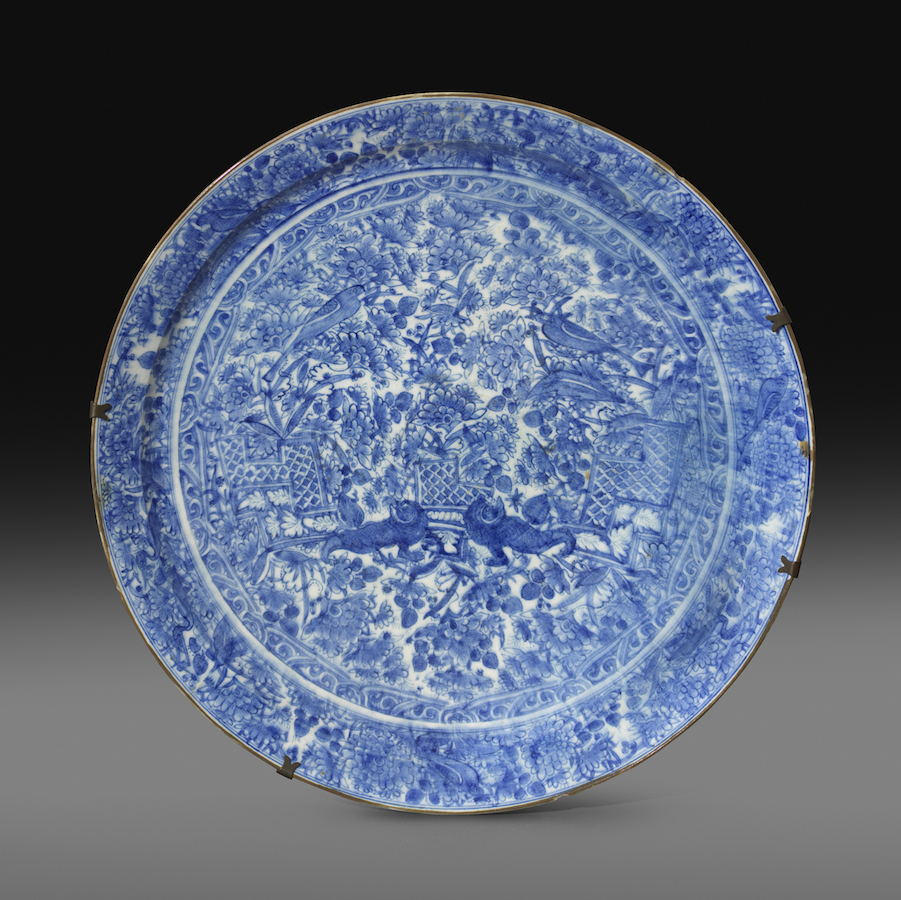 A large Safavid blue and white pottery dish, Persia, late seventeenth century, Painted in cobalt blue under a transparent glaze, the field depicts a pair of adorned guardian lions supporting a trellis platform. 53.8 cm. diameter; 10.6 cm. height A large Safavid blue and white pottery dish, Persia, late seventeenth century, Painted in cobalt blue under a transparent glaze, the field depicts a pair of adorned guardian lions supporting a trellis platform. 53.8 cm. diameter; 10.6 cm. height