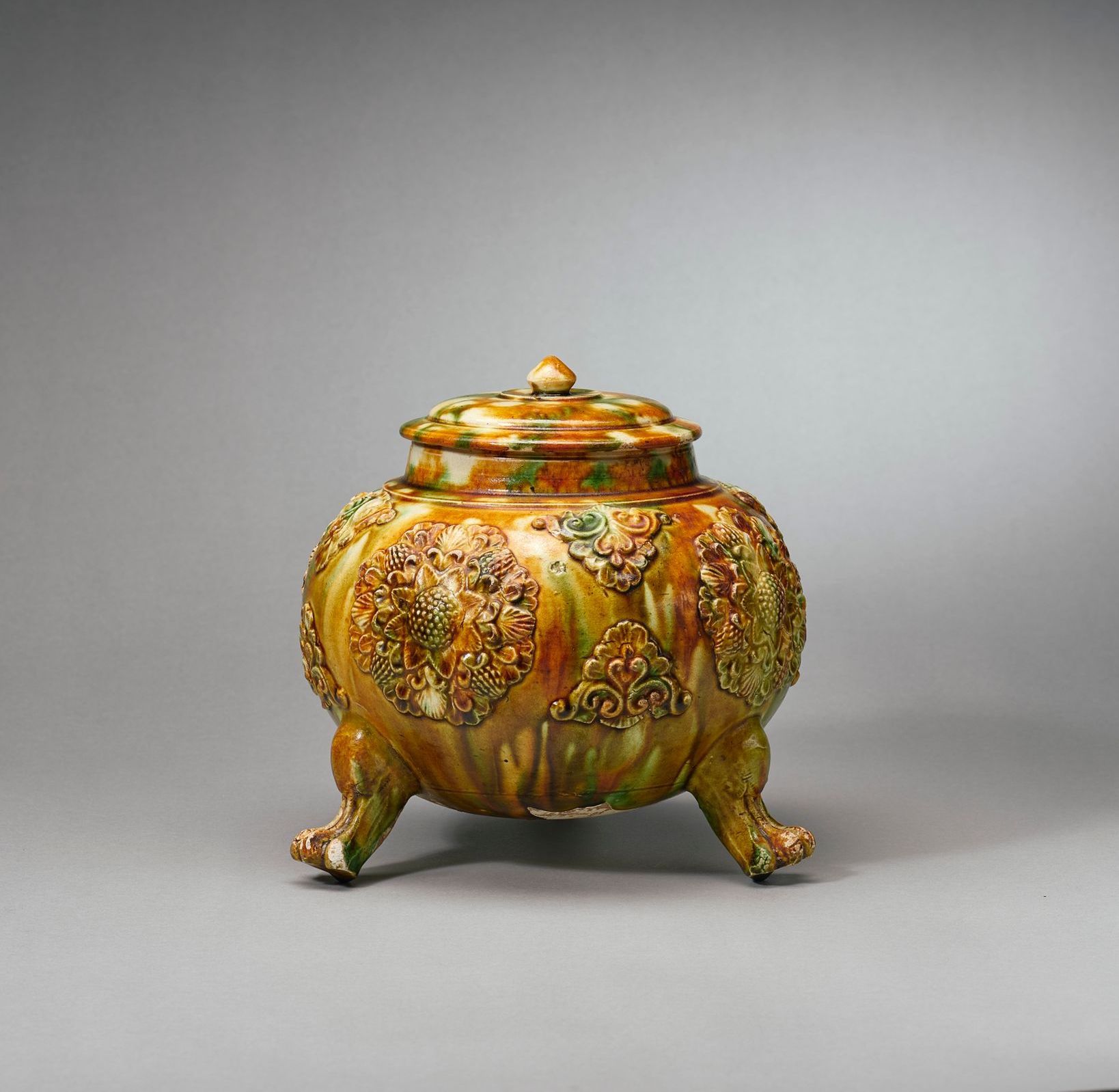 A rare, finely-moulded sancai-glazed pottery globular tripod jar and cover, Tang Dynasty (AD907-618)